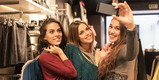 Mujeres felices compartiendo su experiencia con los clientes usando las redes sociales en su tienda favorita