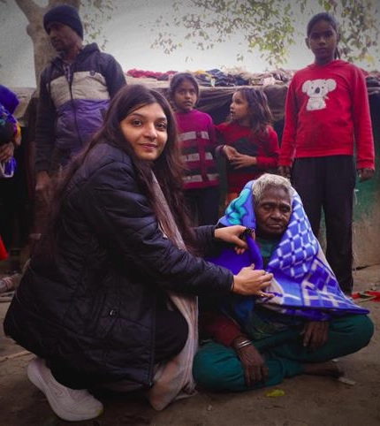 Shinu Tripathi, Motion Graphic Designer at Chetu, gives a woman a blanket to keep her warm.