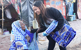 Shweta Purohit, Senior HR Executive, distributes a blanket to an elderly woman during Chetu’s Winter Gear Drive in Noida.